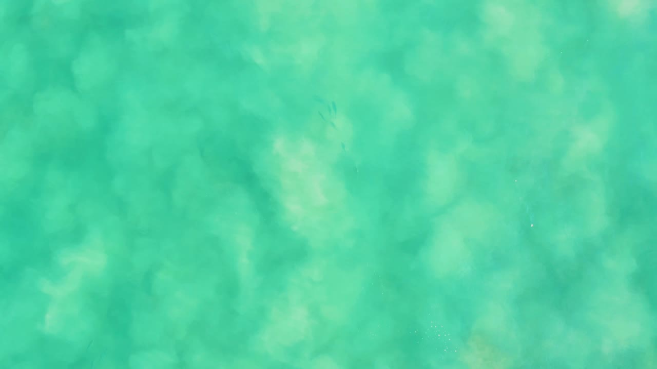 Shallow turquoise sea covers the frame, with pale sandy patches under the surface at Los Frailes and no visible people or objects above the water.