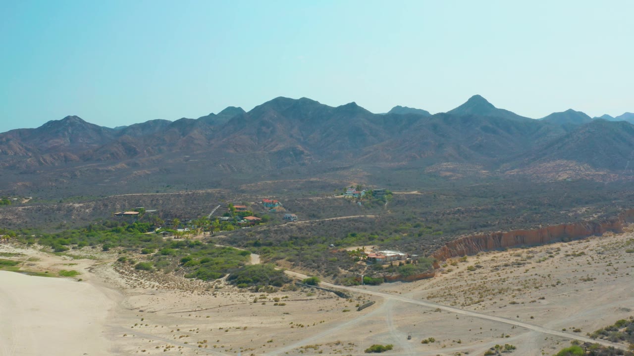 Desert roads and scrub below mountain ridge