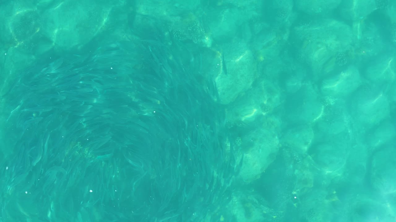 Shallow turquoise water in Los Frailes, Los Cabos ripples across rounded rocks with bright refracted highlights and no visible people.