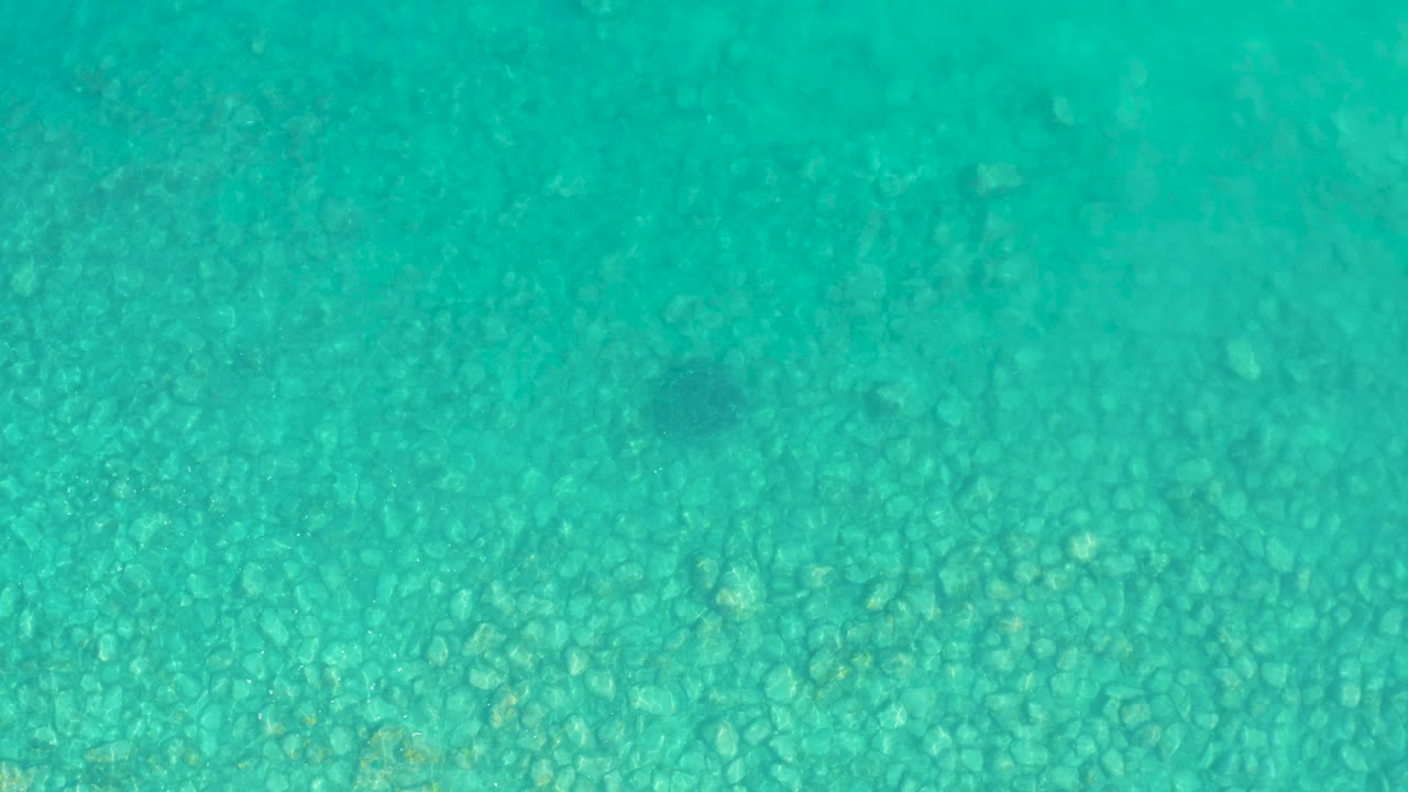 Turquoise water over a rocky seabed.
