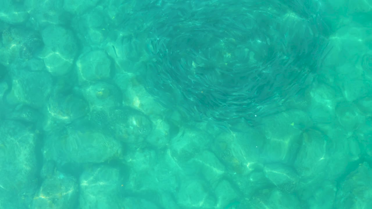 Clear pool water in Los Frailes Los Cabos, Mexico, with a darker circular ripple pattern over the visible tiled bottom and no visible people.