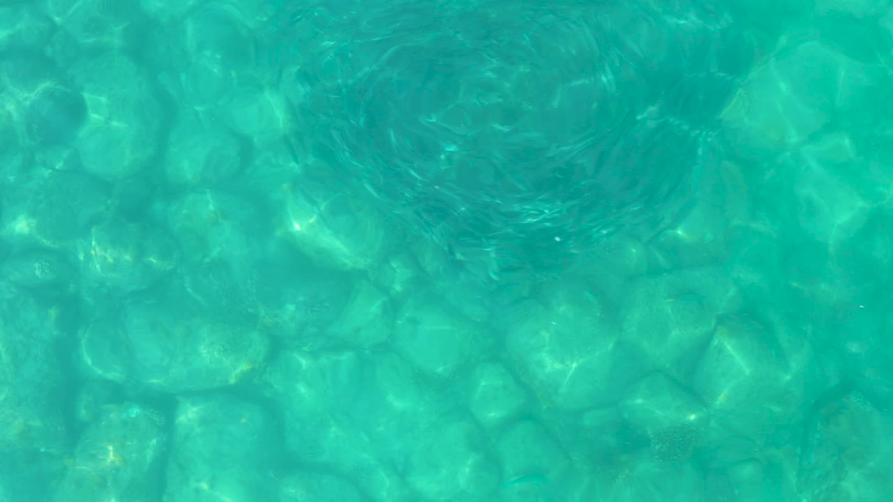 Aqua pool water from the Los Frailes Los Cabos collection shows softened ripples and light bands over the tiled bottom, with no visible people.