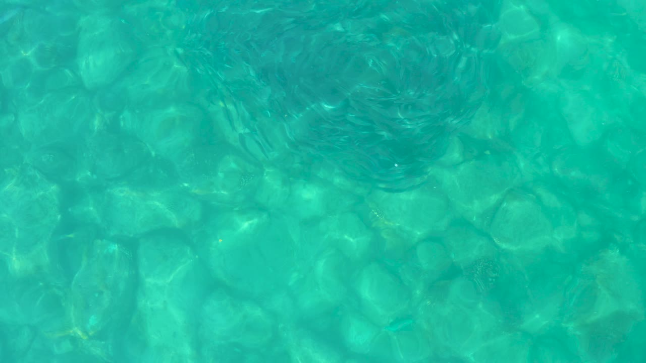Turquoise shallow water over submerged rocks.