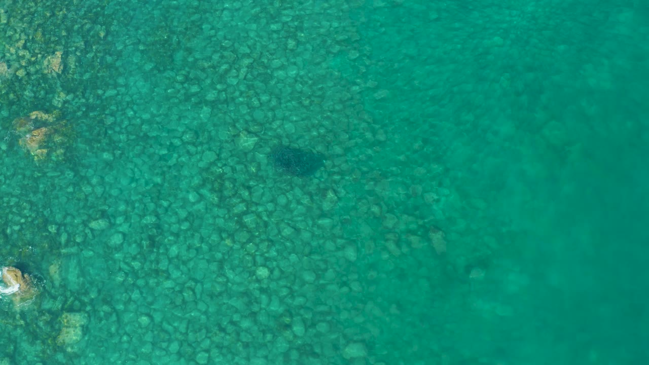 Clear green-blue water showing stones and a pale object near the left edge.