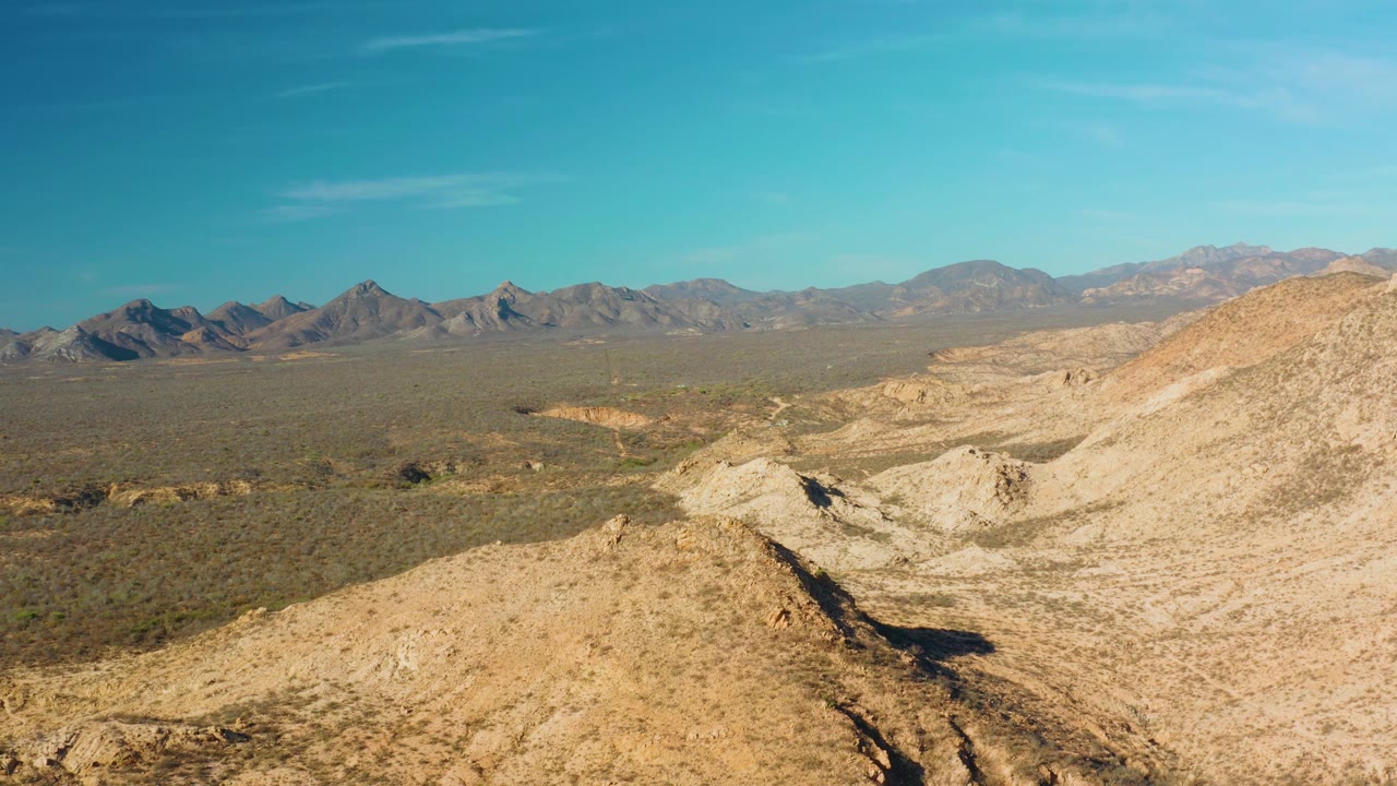 Broad arid valley with foreground ridge and blue sky