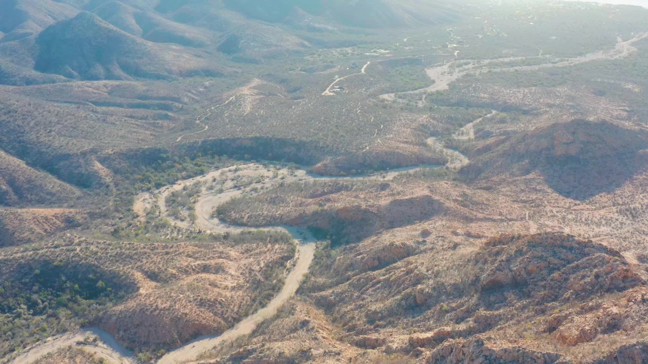 Winding road curves around dry ridges and scrub.