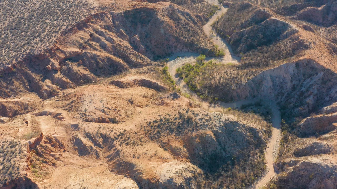 Aerial view of a winding dirt road through dry rocky hills