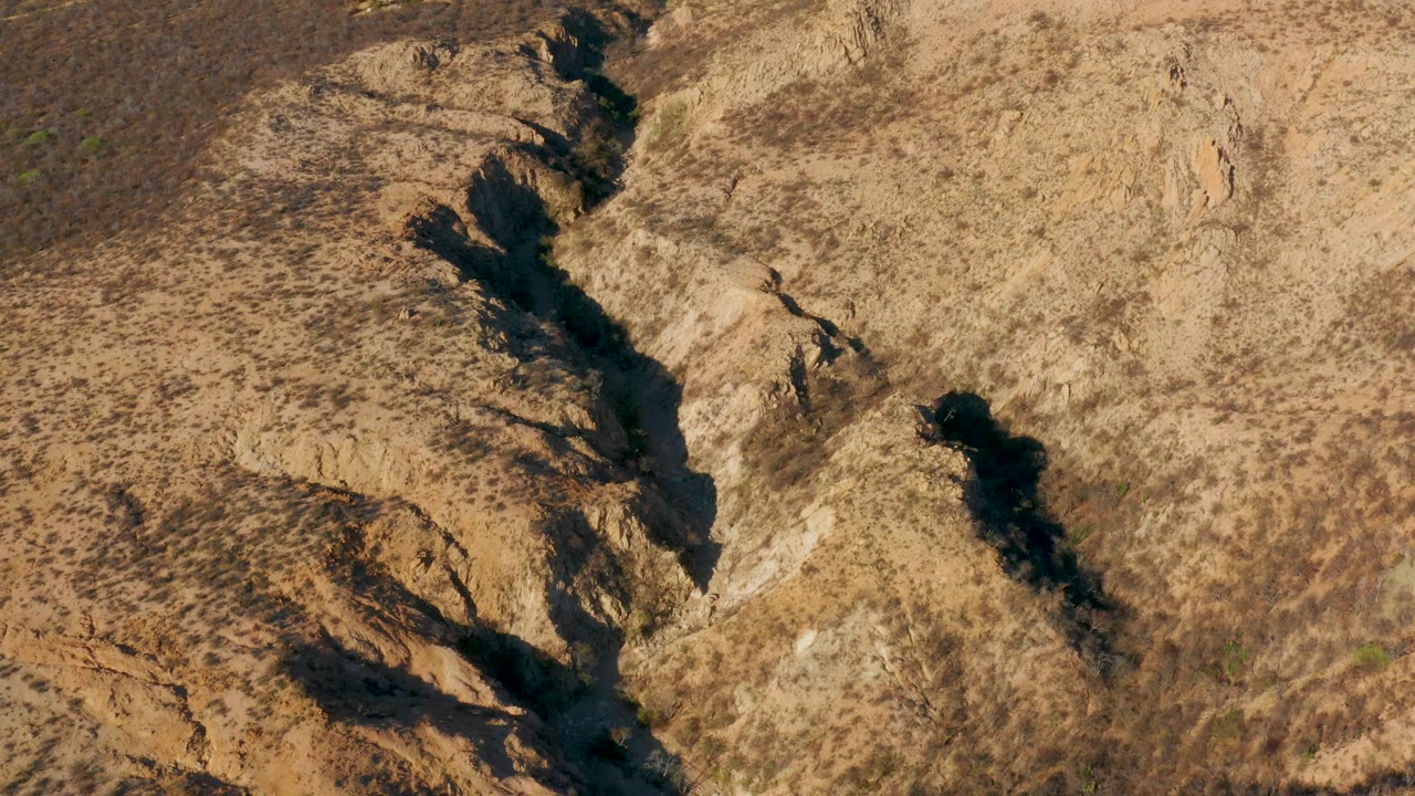 Aerial view of a diagonal rocky wash and narrow water channel.