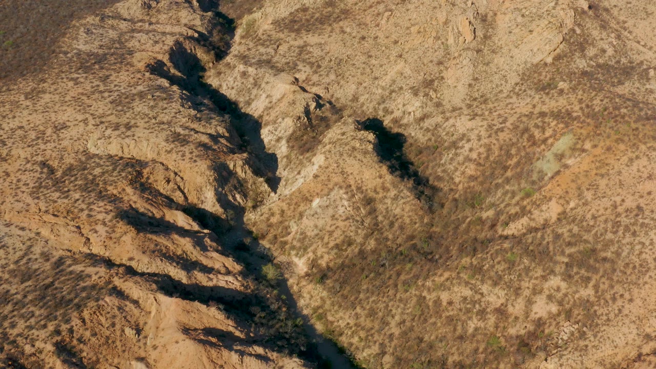 Rocky desert wash with a narrow watercourse and strong channel shadows.