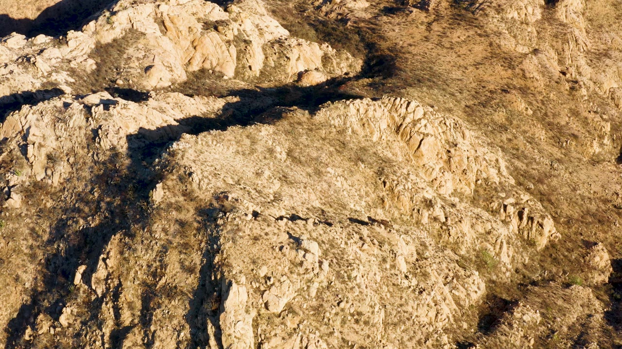 At 0:02, the overhead composition shows dry Cabo Pulmo rock formations with darker ravine-like shadow lines and no visible people.