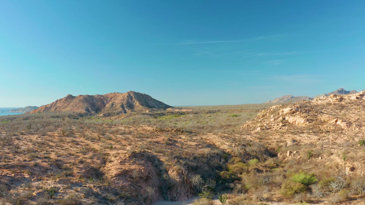 Cabo Pulmo desert view at 0:01 with the rocky foreground wash lower in frame, hills across the left, and no visible people.
