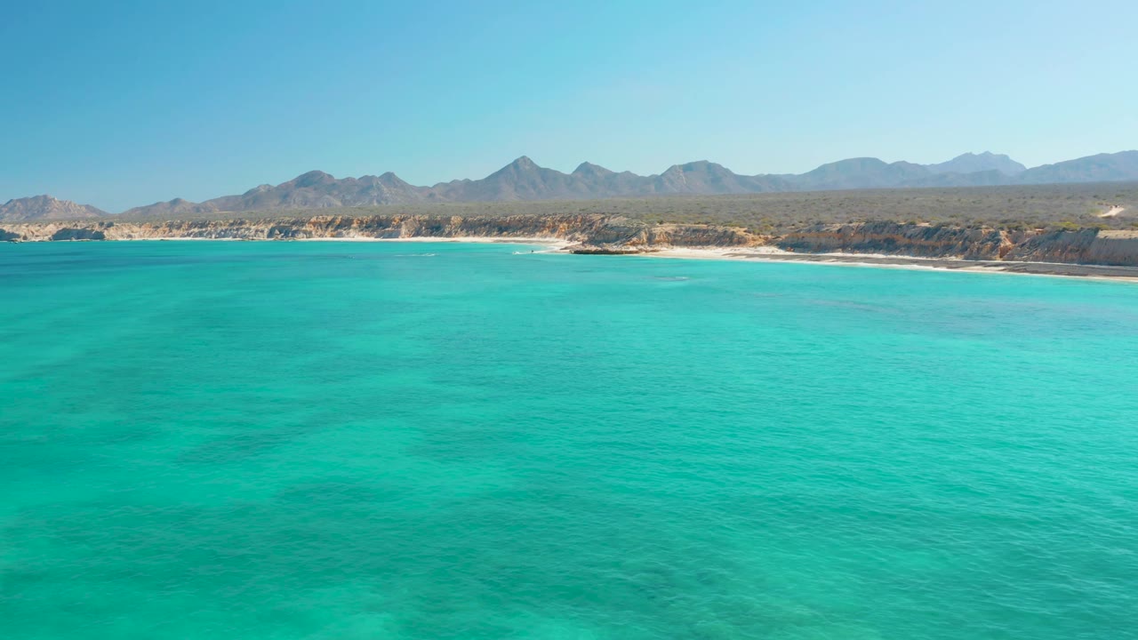 Aerial coastline with turquoise water and rocky mountain backdrop