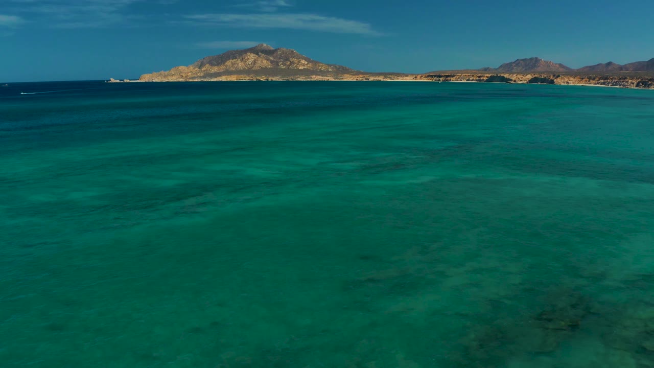 Clear teal water below a distant mountain shoreline