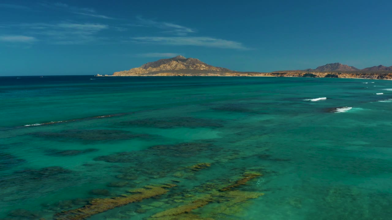 Turquoise ocean with white surf lines near distant island