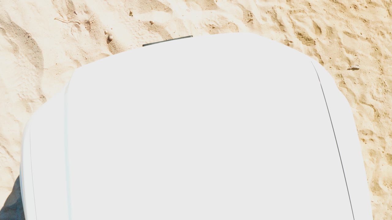 White lounge chair cropped over light brown sand.