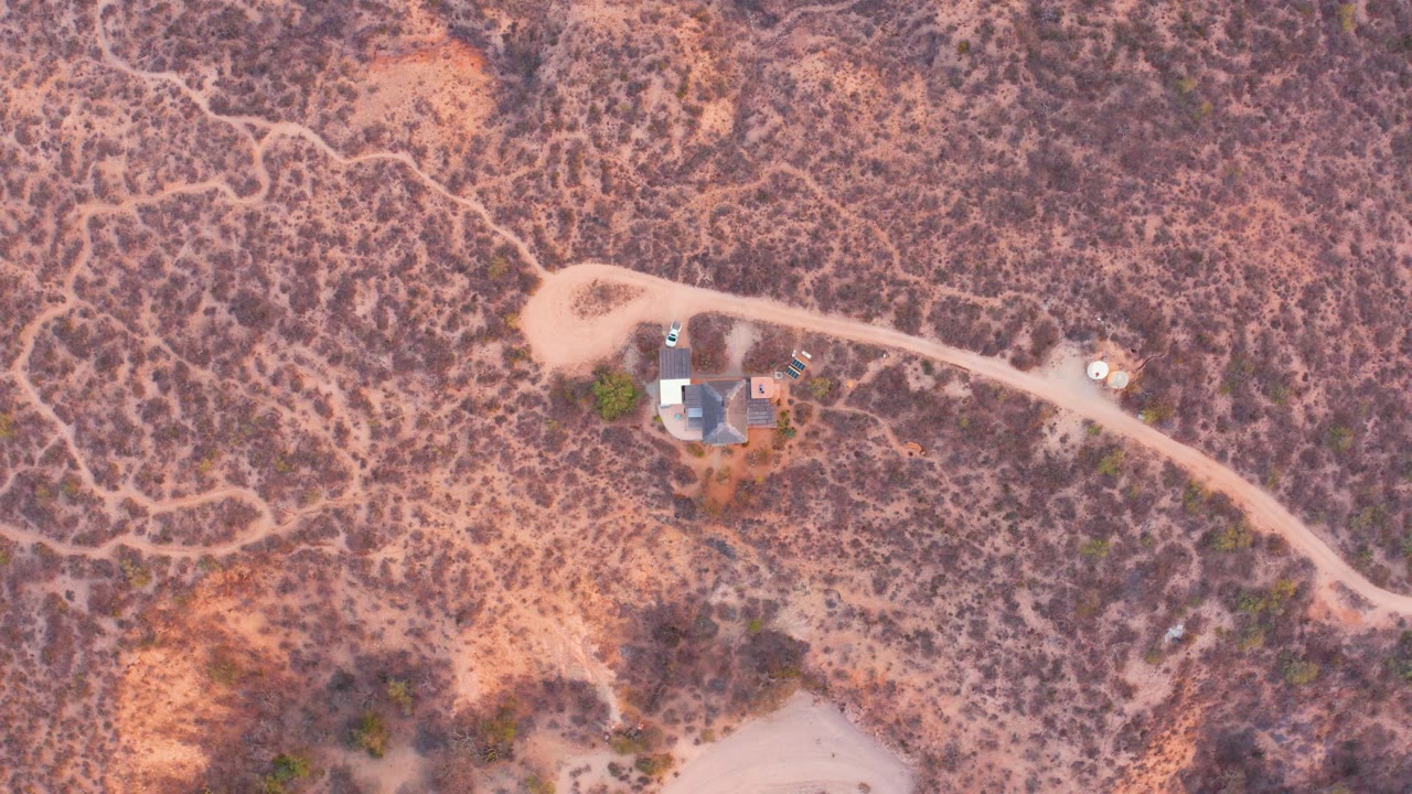 Aerial view of a desert home and road through scrub