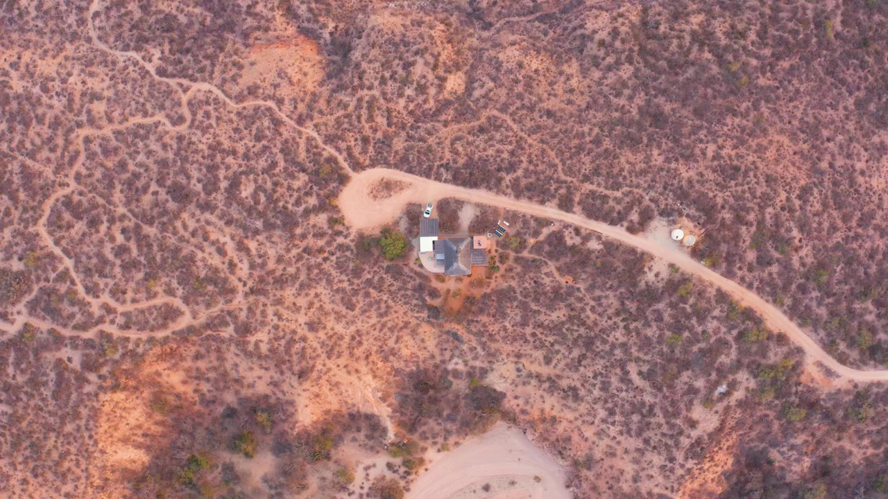 Remote house and curved dirt road in dry scrub