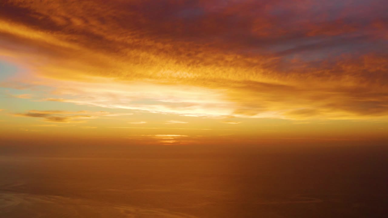Cabo Pulmo ocean sunset with dense orange cloud layers overhead, a darker water band at the horizon, and no visible people.
