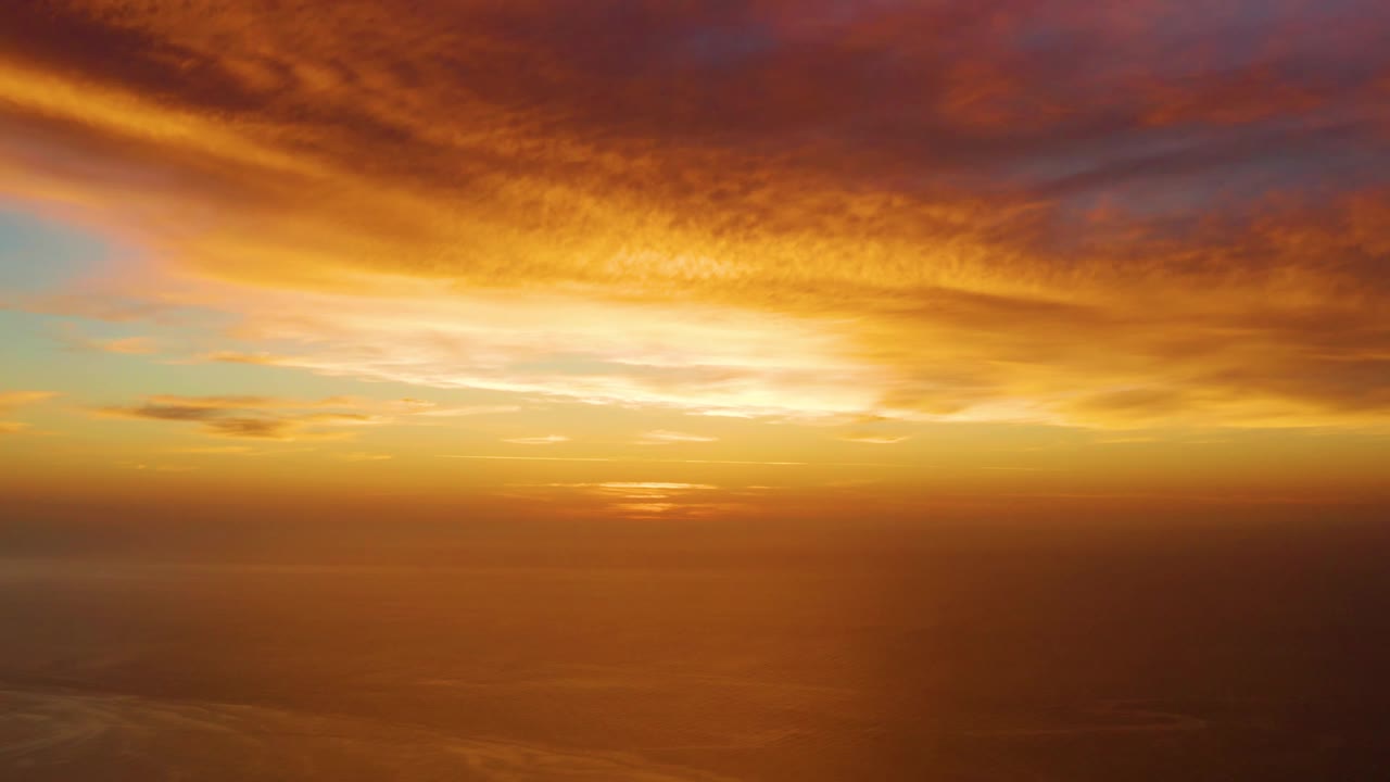 The low sun sits near the ocean horizon at Cabo Pulmo while orange and pink clouds stretch across the upper frame, with no visible people.