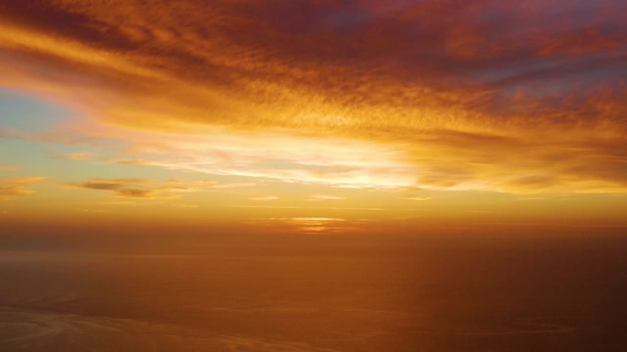 Early frame showing the bright sunset glow centered above the ocean horizon in Cabo Pulmo, with layered orange and purple clouds and no visible people.