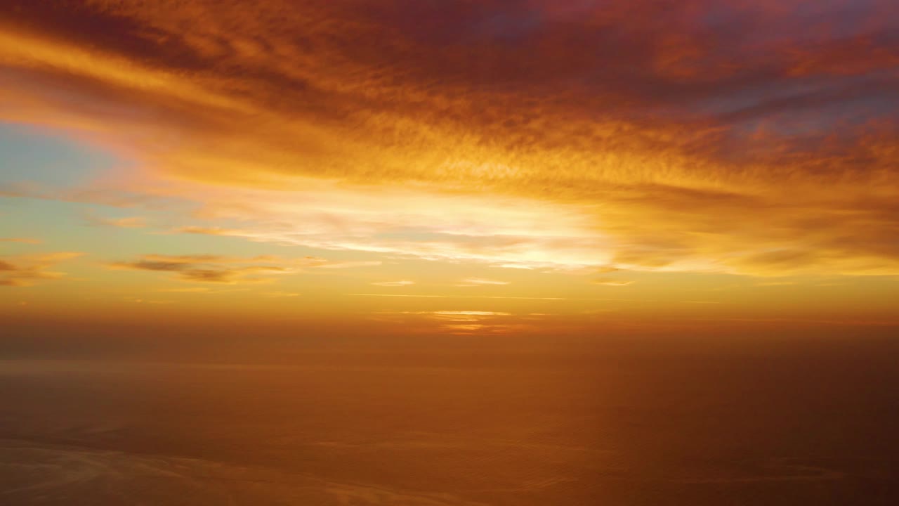 A bright orange cloud band sits above reflective ocean water in Cabo Pulmo, with the horizon low in frame and no visible people.