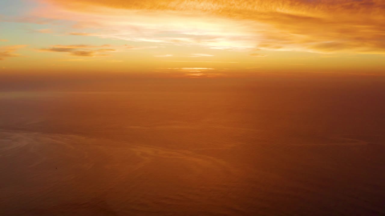 At 0:01, orange and gold clouds stretch across the Cabo Pulmo ocean horizon with calm water below and no visible people.