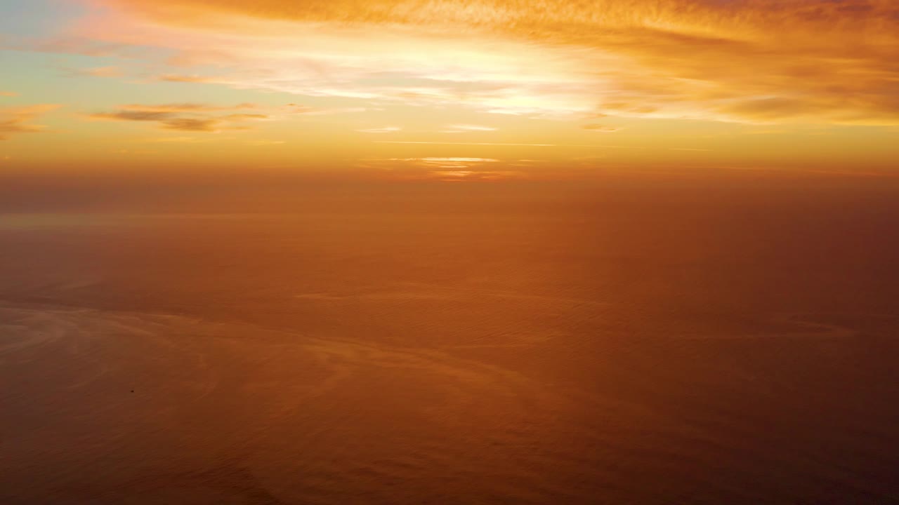 At 0:03, a warm orange haze sits over the Cabo Pulmo ocean beneath scattered sunset clouds and no visible people.