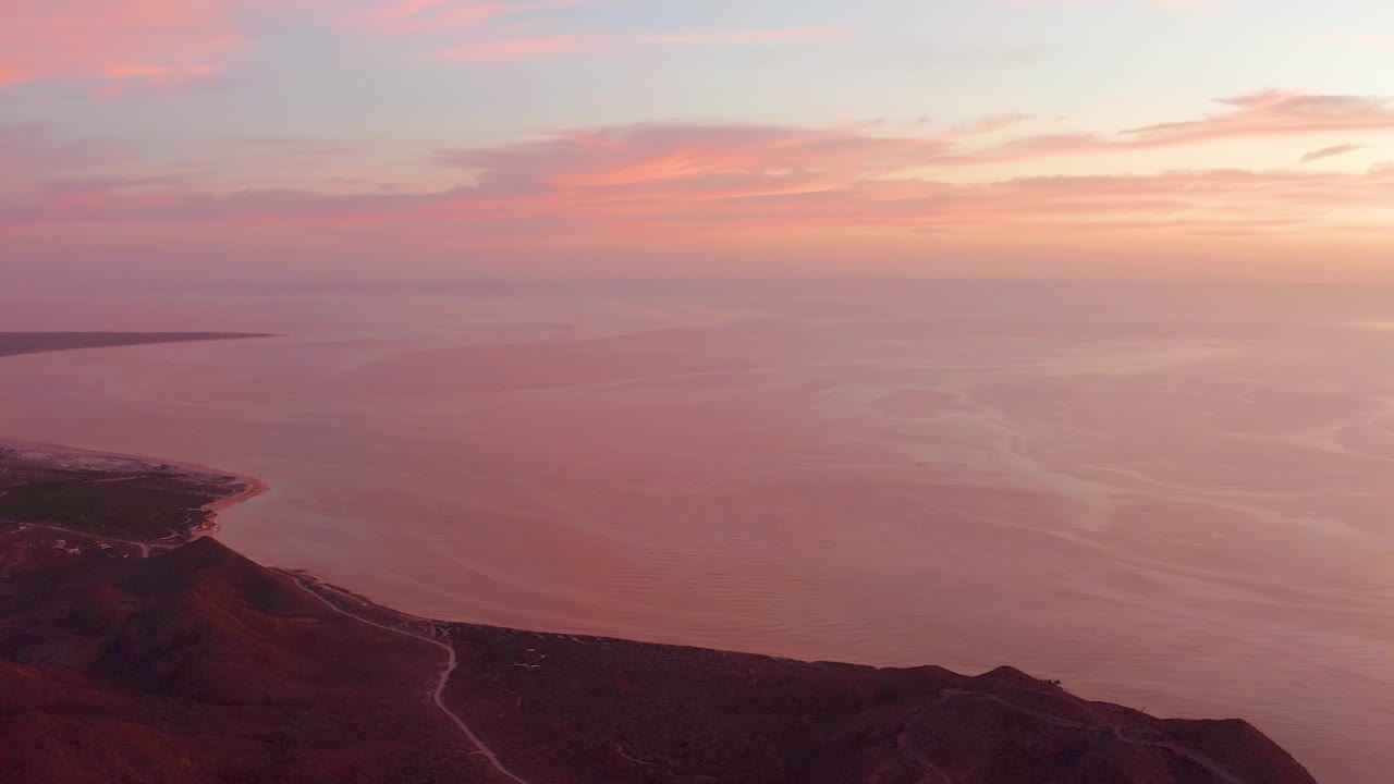 Coastal headland and calm water beneath sunset clouds