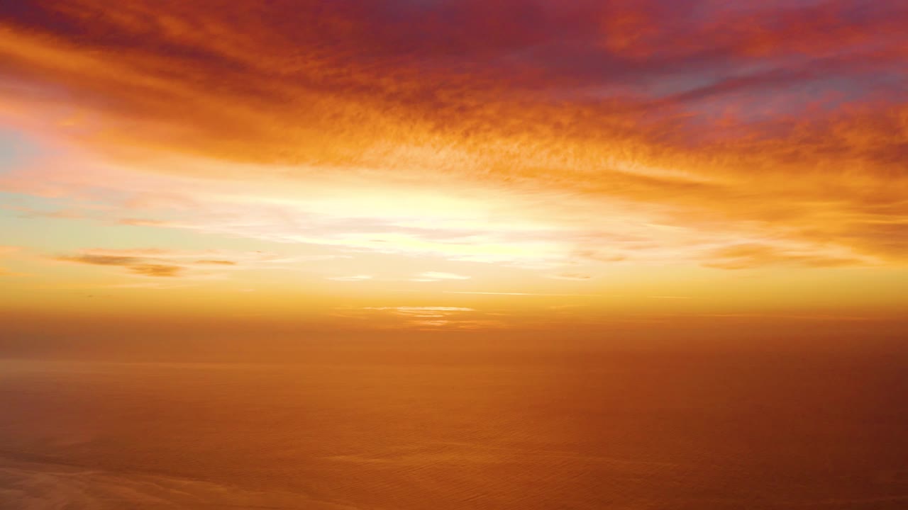 At 0:01, the Cabo Pulmo sunset frame keeps the bright golden cloud break centered above a thin calm ocean band, with no visible people.