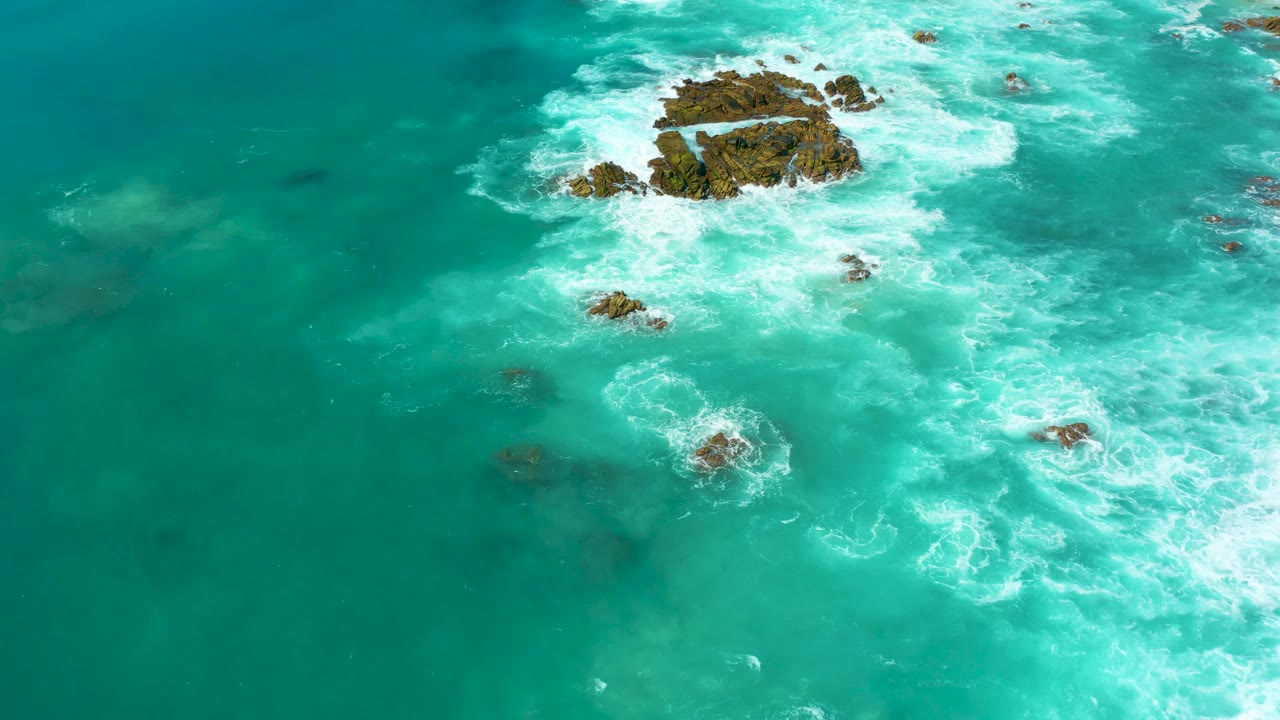Turquoise ocean waves breaking around rocky outcrops