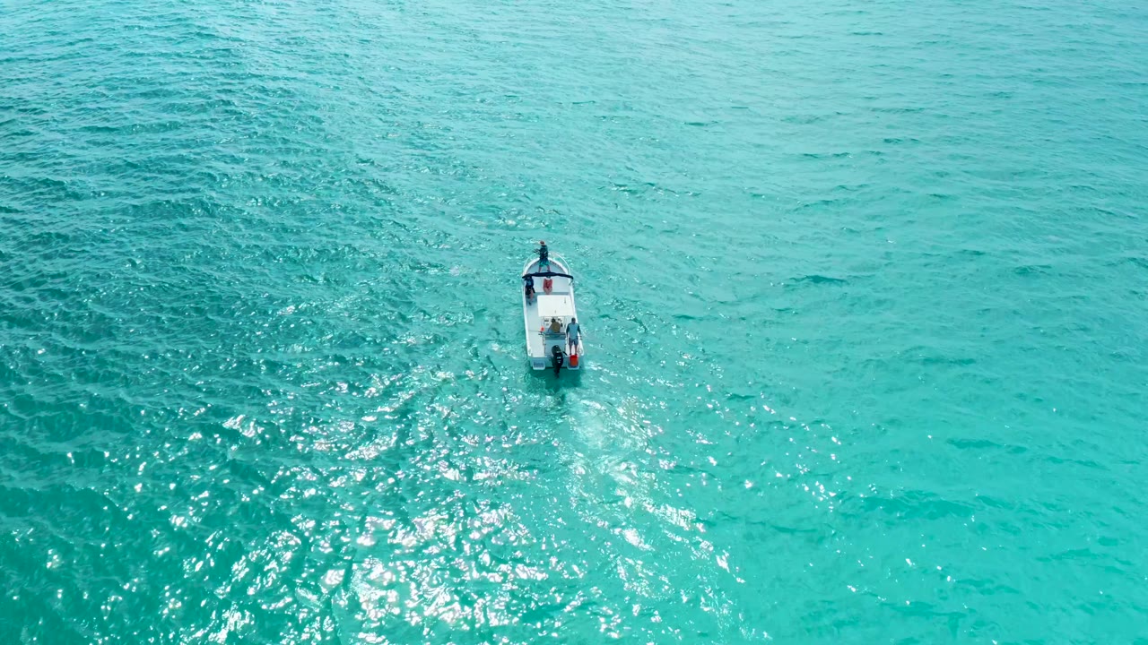 Aerial view of the small boat held near center over rippled turquoise water at Marquis Los Cabos, with no visible people.