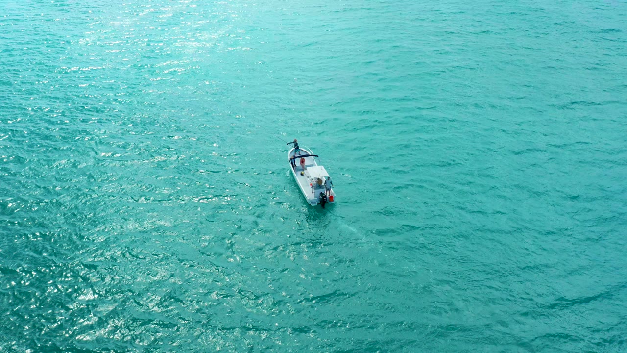 Overhead view of a small boat near the upper left area of turquoise water at Marquis Los Cabos, with sunlit ripples and no visible people.
