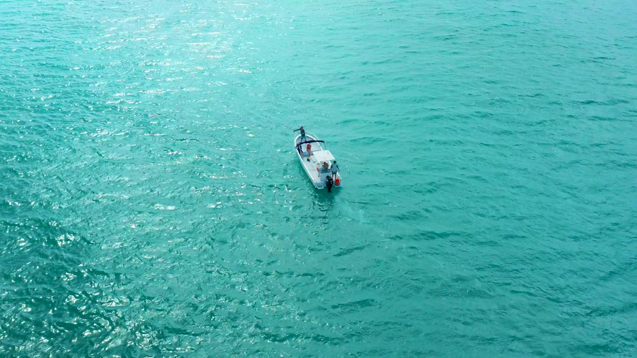 Overhead boat with ripples on clear blue-green water.