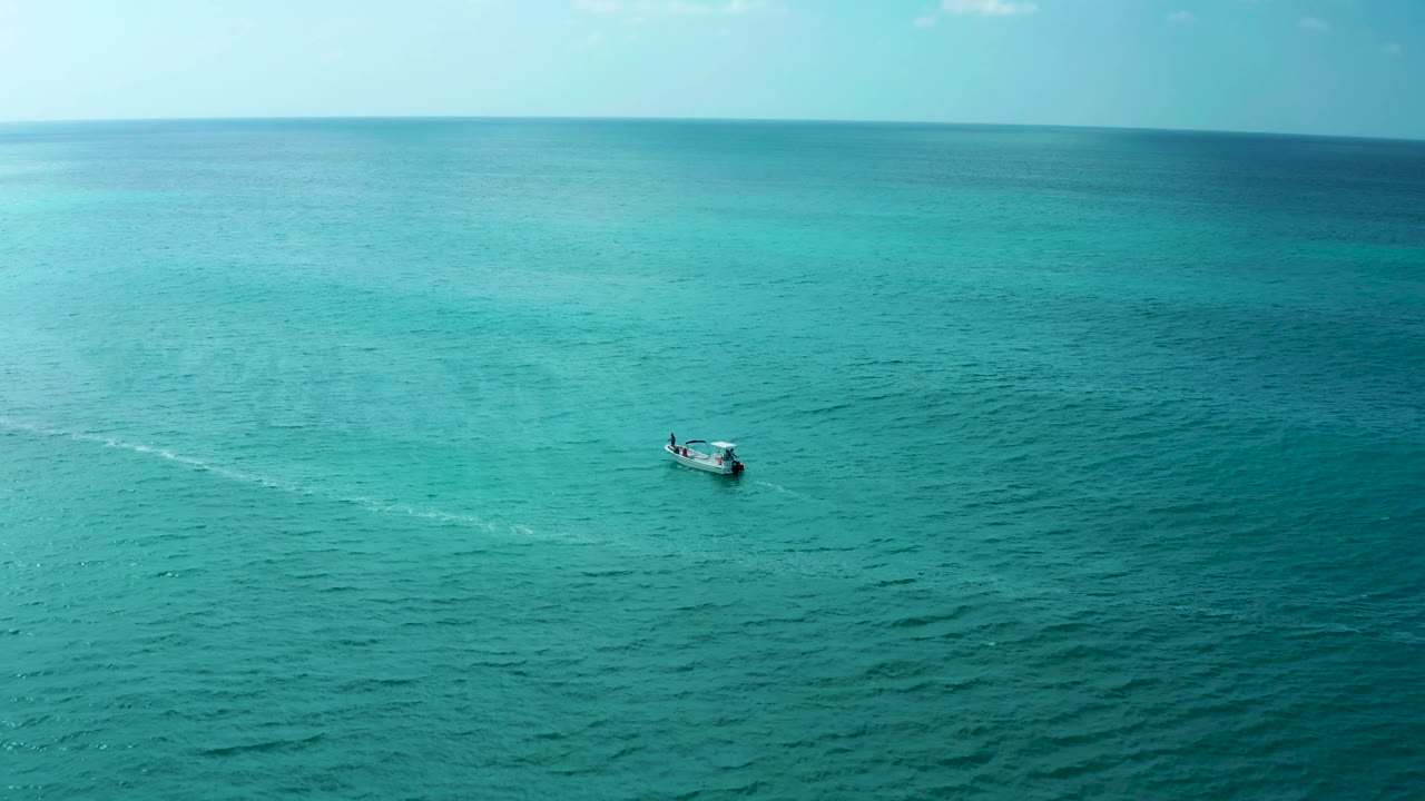 Midway through the clip, the boat remains small against the turquoise sea near Marquis Los Cabos, with its white wake spreading behind it and no visible people.