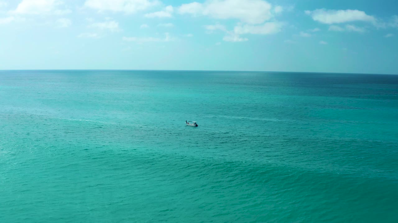 At Marquis Los Cabos in Baja California Sur, the boat sits slightly farther right on calm turquoise water, with a pale wake line behind it and no visible people.