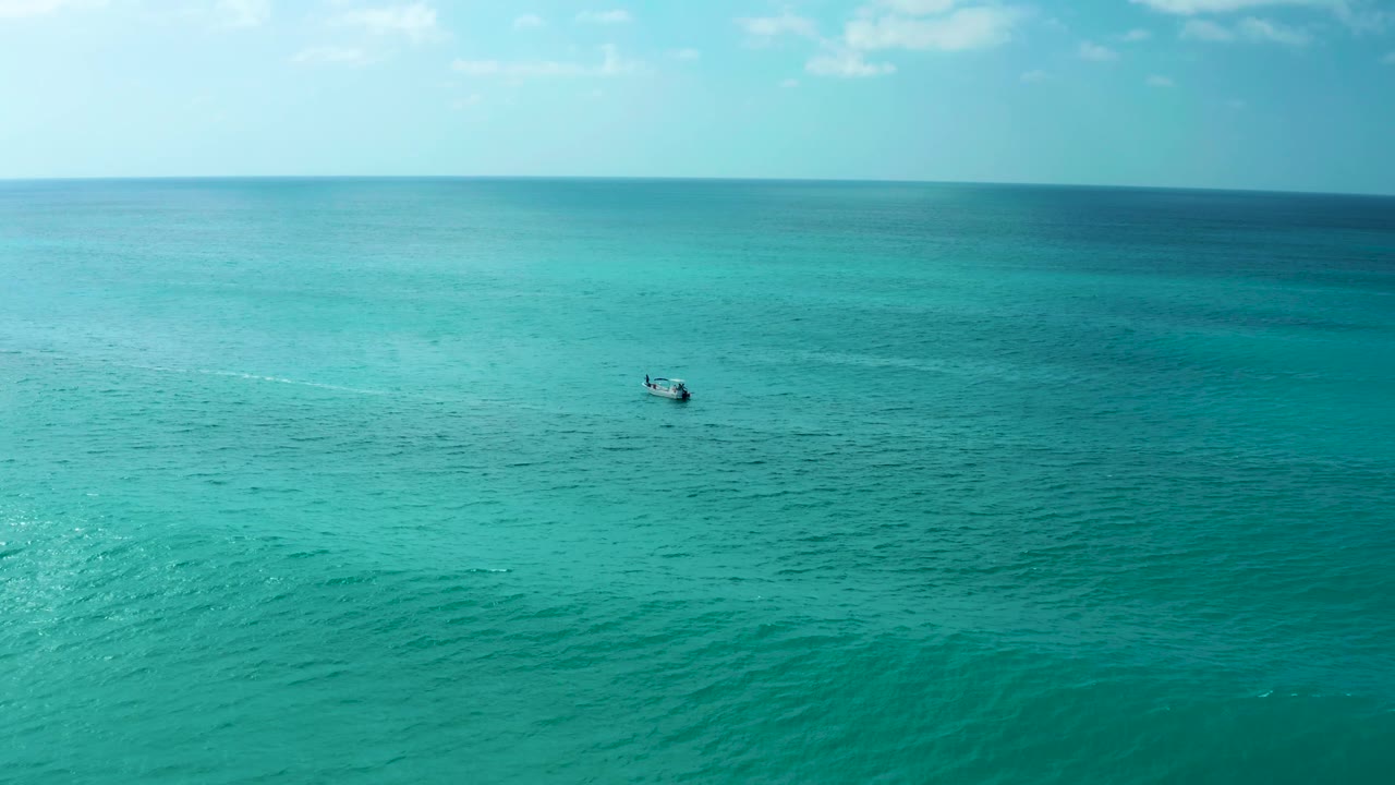 At Marquis Los Cabos in Baja California Sur, the small boat is low and left of center on textured turquoise water, with a thin wake and no visible people.
