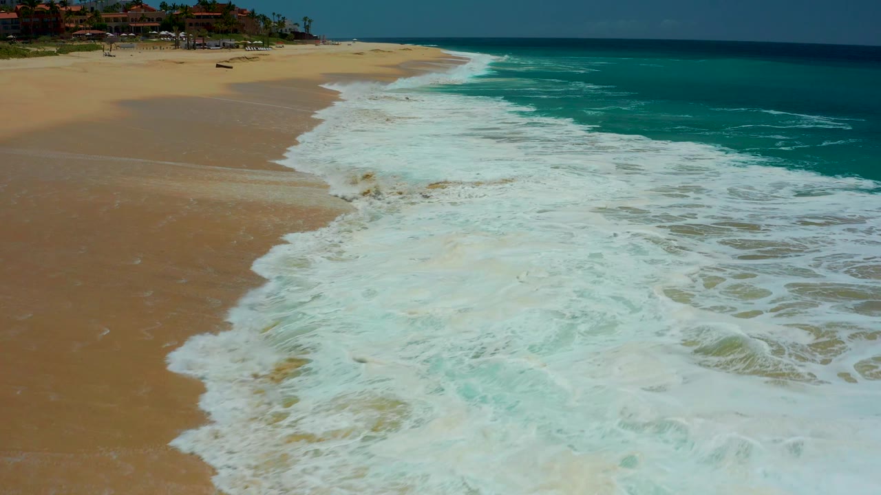 White wave foam spreading farther across the beach shoreline.