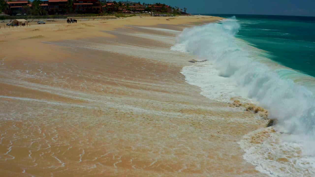 Large wave beginning to break along a sandy beach