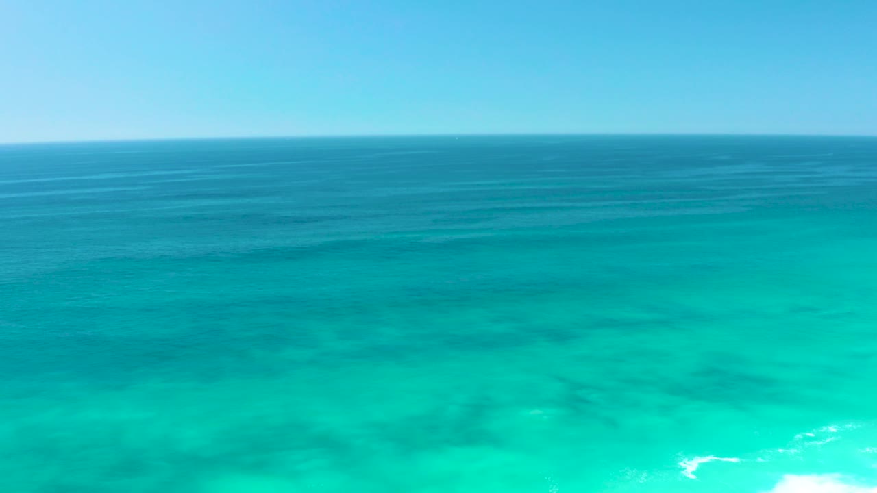 Opening frame of turquoise ocean off Dreams Los Cabos with deep blue water near the horizon, lighter shallows below, and no visible people.