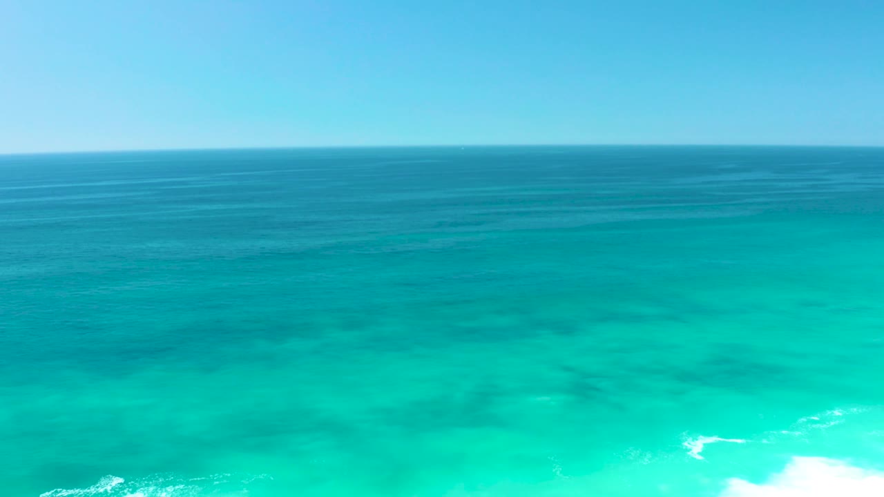 Open turquoise ocean with white foam growing along the lower edge.