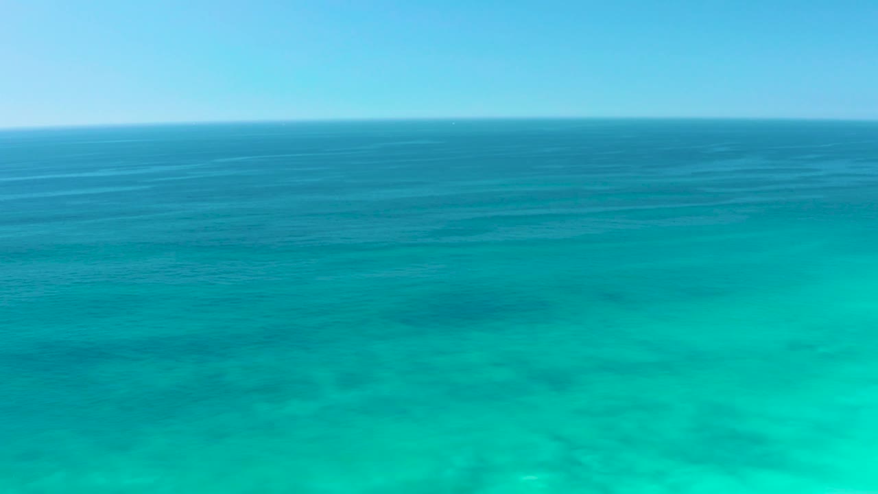 Open ocean view at Dreams Los Cabos with bright turquoise foreground water, darker midground sea, a pale sky, and no visible people.