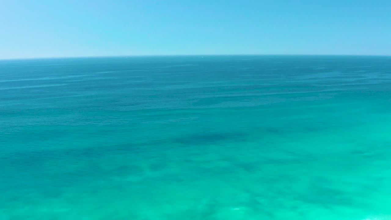 Aerial-looking ocean frame at Dreams Los Cabos, showing layered turquoise and blue water under a clear sky with no visible people.
