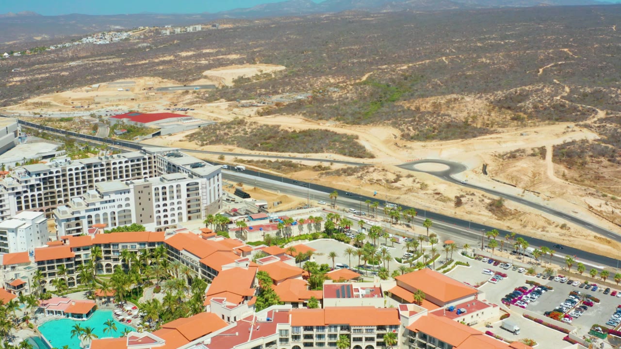 Aerial shot of resort edge, road, cars, and desert hillside.