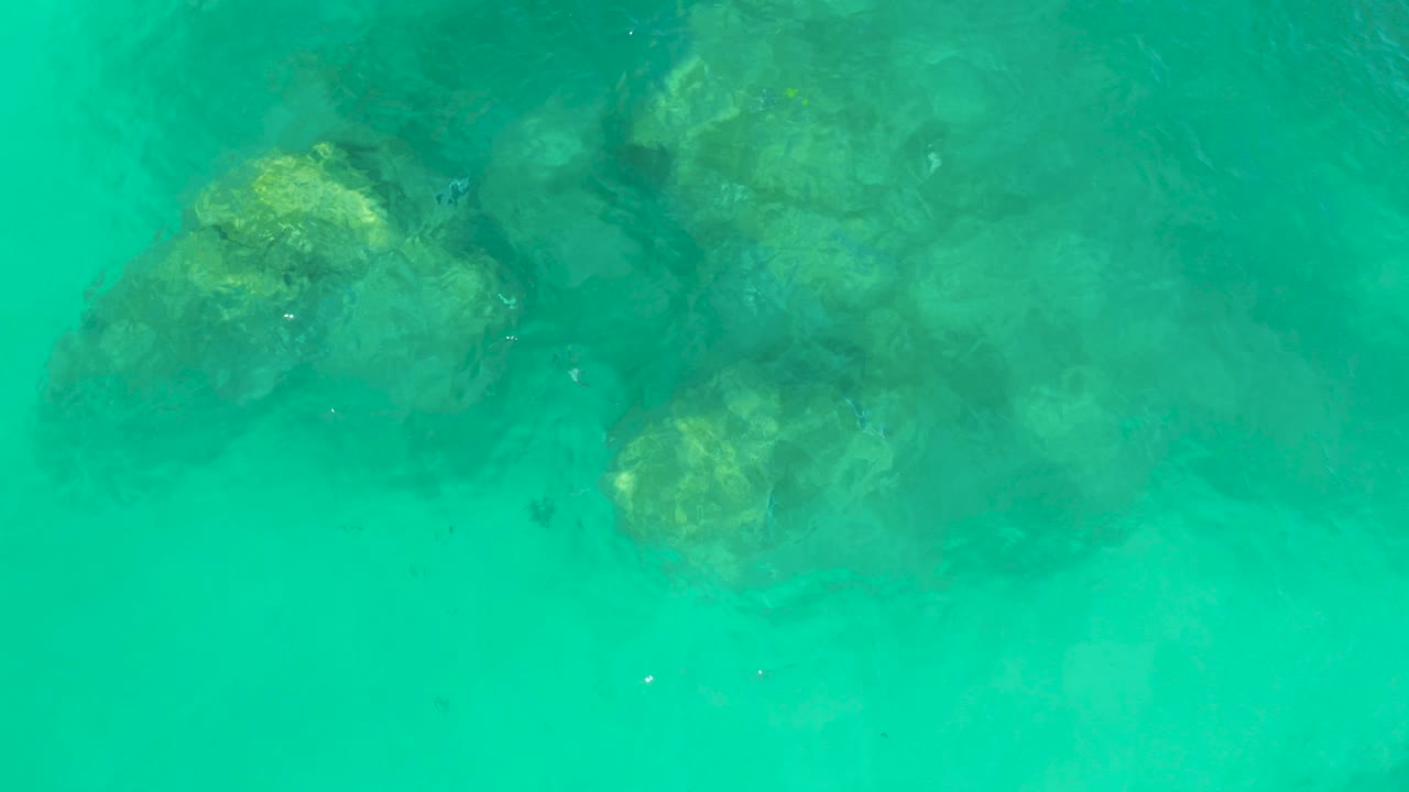 Turquoise water over submerged rocks.