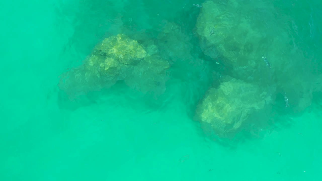 Large submerged rock cluster beneath green turquoise water.