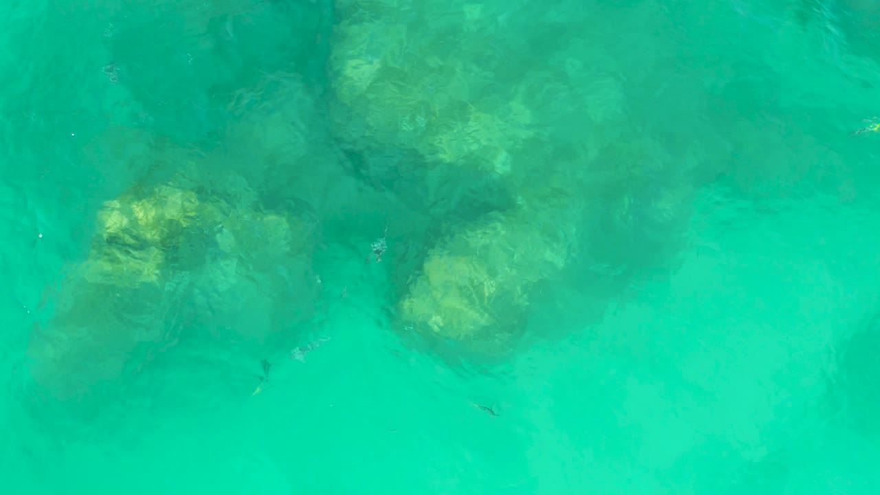 Turquoise water ripples over several pale submerged rocks at Dreams Los Cabos, softening their edges and showing no visible people.