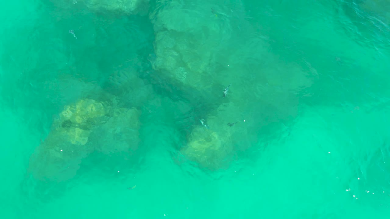 At 0:01, green-blue water shifts over submerged rocks near the upper and lower parts of the frame, with no visible people.