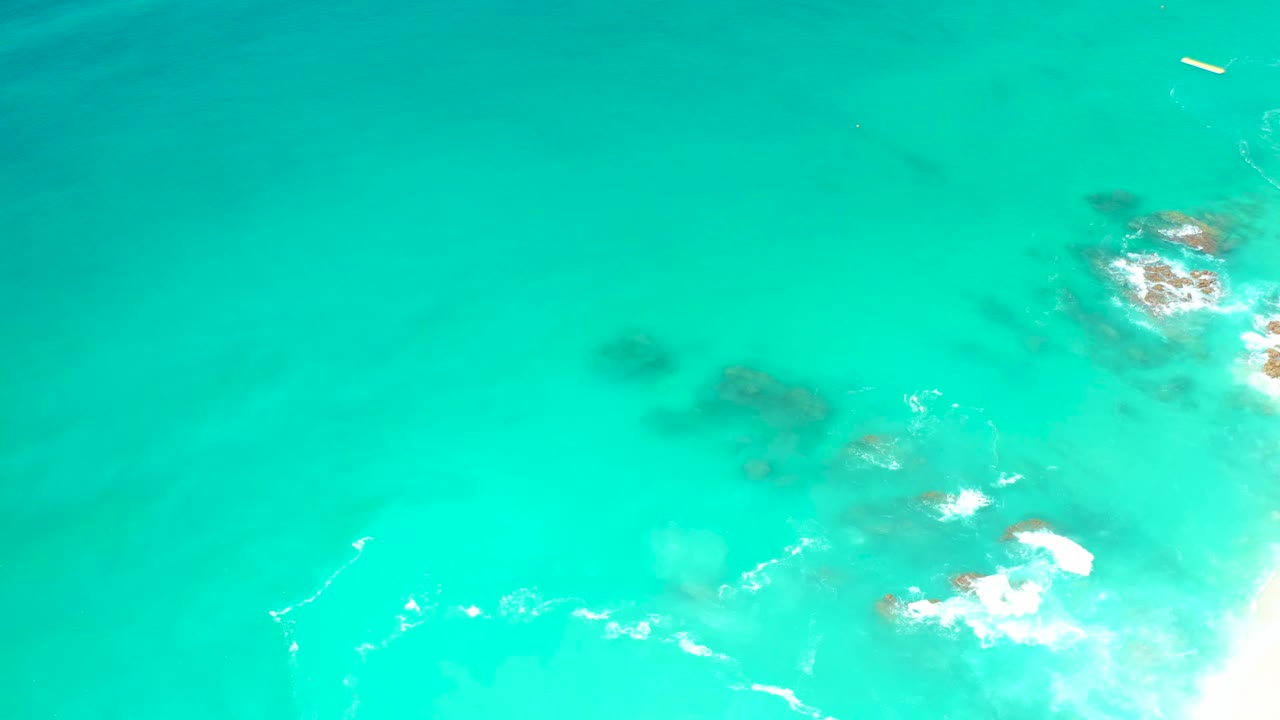 Turquoise ocean water with white foam over submerged rocks