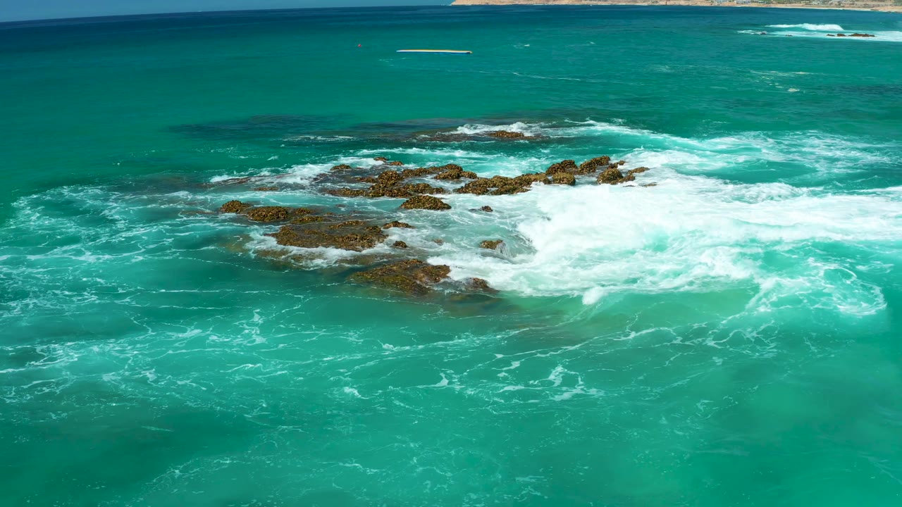 Aerial view of waves churning around rocky shore
