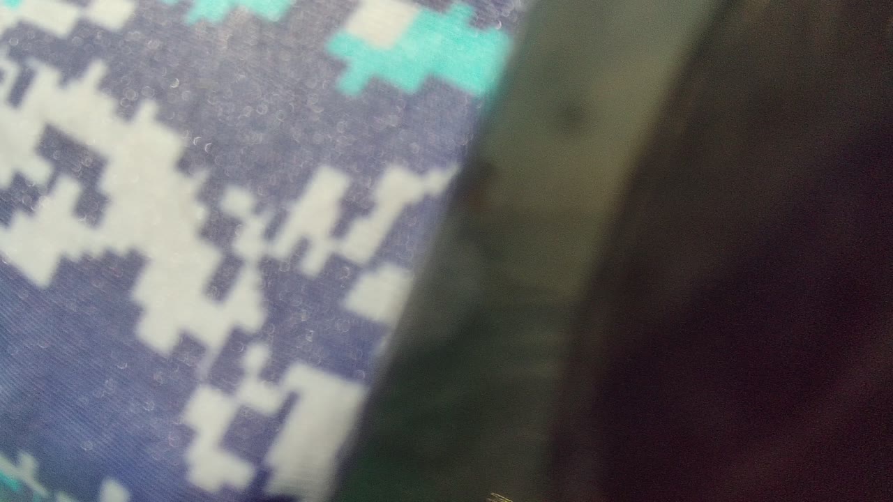 Close out-of-focus view of blue digital camouflage fabric and dark snorkel gear at the start of the Palmilla Los Cabos clip, with no clear face visible.